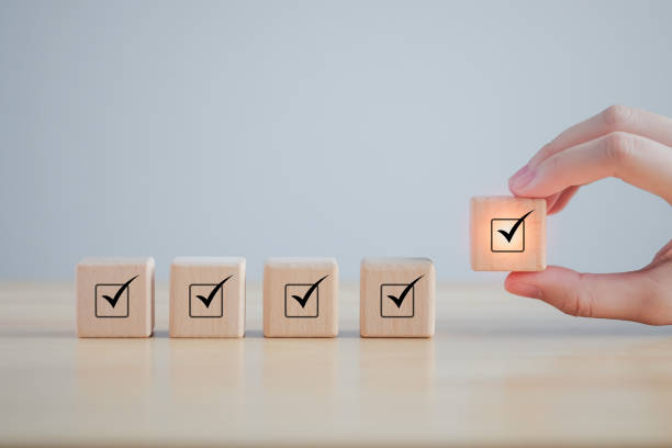 istock Checklist, Task list, Survey and assessment. Quality Control. Goals achievement and business success. Hand holding Check mark on wooden blocks for complete check list. 1418490644