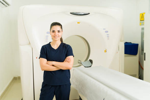 Portrait of a radiologist technician standing next to a screening machine at the lab Female radiologist smiling while waiting for a patient for medical test or cat scan at the imaging laboratory x ray image medical occupation technician nurse stock pictures, royalty-free photos & images