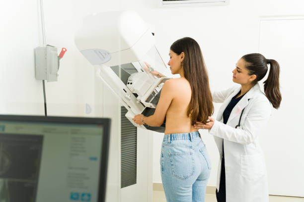 Patient getting a mammography test at the imaging center to prevent breast cancer Rear view of an hispanic young woman getting a mammogram to check for breast cancer with the help of a female doctor at the imaging diagnostic center medical examination room stock pictures, royalty-free photos & images