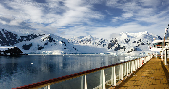 The hallmark of expeditions in Antarctica is the fantastic scenery of mountains, glaciers, icebergs, and sea. In this image the deck and rail draw the eye to the mountains and the icebergs.