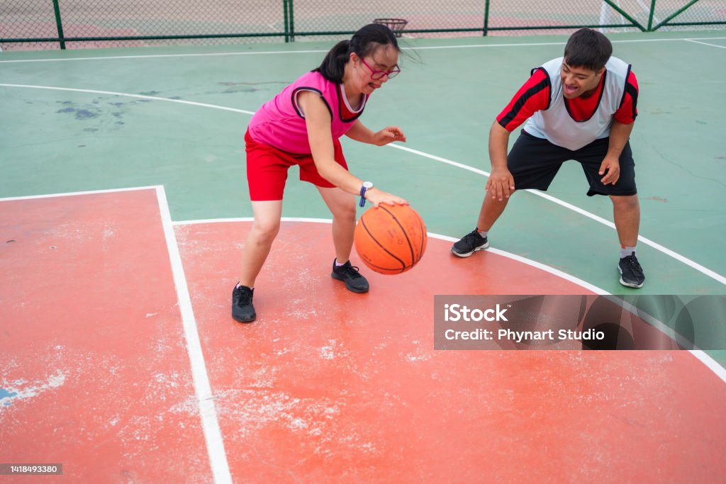 Young Couple With Down Syndrome Playing Basketball Stock Photo