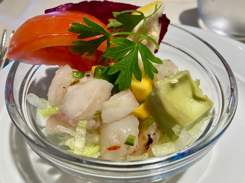 Seafood salad served in white plate closeup. Octopus and tuna fish with lemon salad appetizer on restaurant table. Mediterranean cuisine recipe. Luxury sea food dinner.