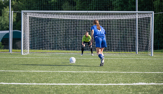 Two female soccer players with soccer ball playing on soccer field. Penalty shot. Sport and healthy lifestyle concept.