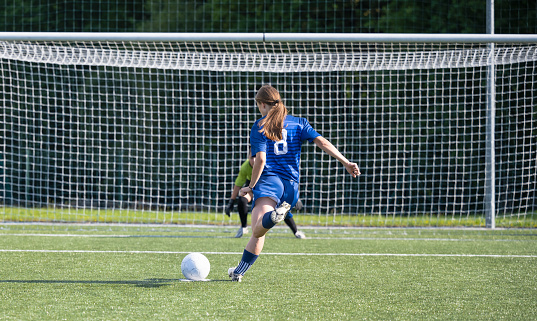 Two female soccer players with soccer ball playing on soccer field. Penalty shot. Sport and healthy lifestyle concept.