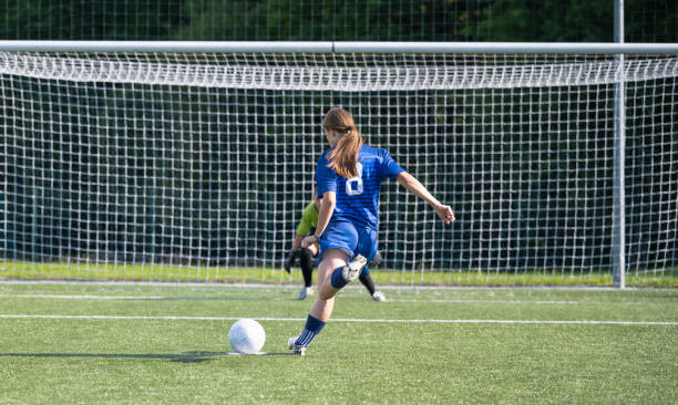 Female Soccer Players - Penalty Shot Two female soccer players with soccer ball playing on soccer field. Penalty shot. Sport and healthy lifestyle concept. womens soccer stock pictures, royalty-free photos & images