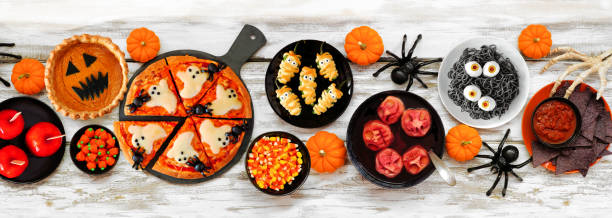 istock Fun Halloween dinner party table scene over a white wood banner background 1418503447