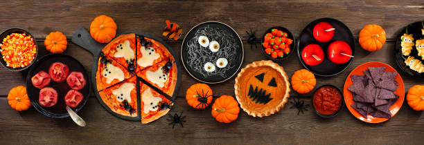 istock Fun Halloween dinner party table scene over a dark wood banner background 1418503448