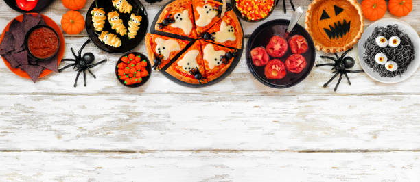 istock Fun Halloween dinner party top border over a white wood banner background 1418503450