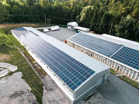 Aerial view of solar panels on the roof of a large storage facility, factory. Providing electricity for the facility, self sufficient facility. Solar panel installation on the roof of a factory. Production of renewable energy concept.