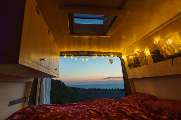 View out of a self built camper van with fairy lights on a colorful sunset over the sea, Normandy, France stock photo