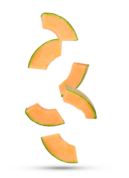 Fresh cantaloupe melon slices falling in the air isolated on white background.