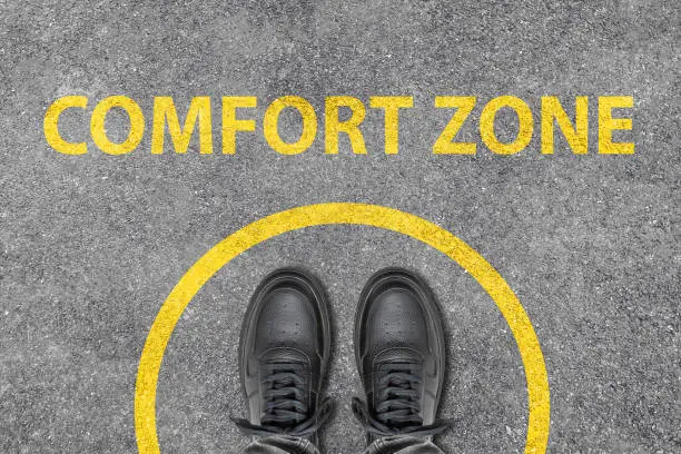 Comfort Zone Concept on asphalt ground. Foot walking shoes top view.