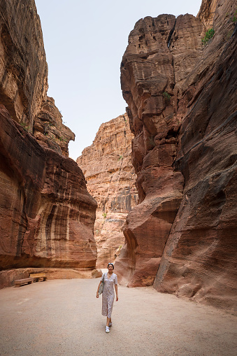 Female tourist walking through Siq passage at Petra famous archaeological site in Jordan's southwestern desert. Dating to around 300 B.C., it was the capital of the Nabatean Kingdom