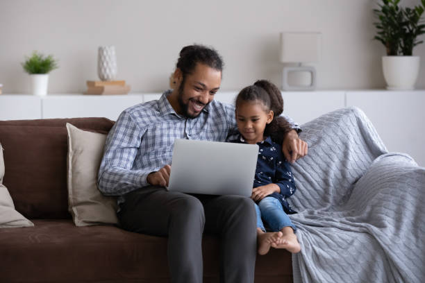 Cheerful dad and little daughter girl using learning app
