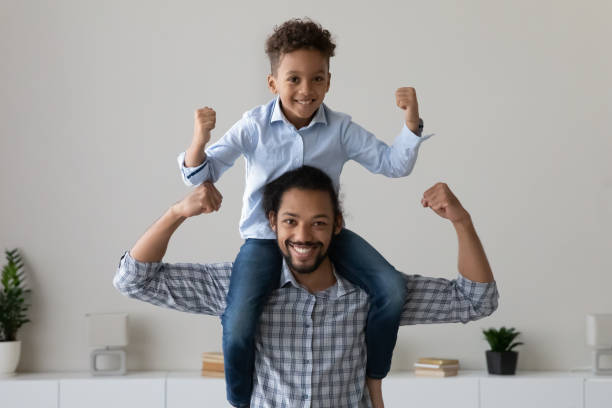 istock Happy joyful little African boy sitting on dads neck 1418516687