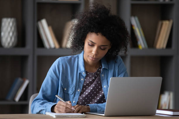 istock Serious young African Black student girl writing notes at laptop 1418516896