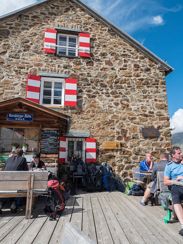 Stubai Valley, Innsbruck-Land, Tyrol, Austria, July 4, 2020: hiker people resting at terrace of Nuernberger Huette, an alpine mountian hut at sunny summer day.