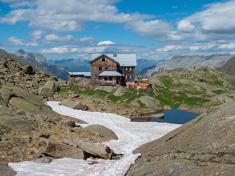 Stubai Valley, Innsbruck-Land, Tyrol, Austria, July 5, 2020: View of Bremer Hutte, an alpine mountian wooden hut with blue lake from melting snow tongues, moutain peaks, sunny summer day