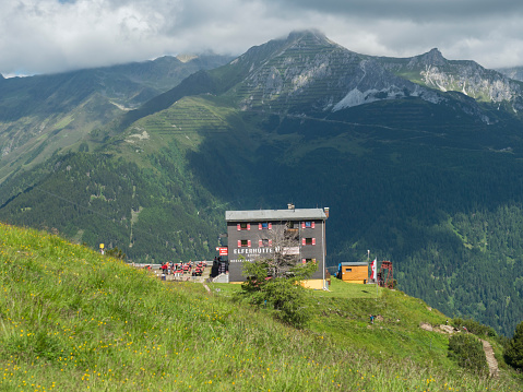 Stubai Valley, Innsbruck-Land, Tyrol, Austria, July 7, 2020: view of Elferhutte, alpine mountian wooden hut with green medow and moutain peaks at top of Stubai valley. Summer blue sky, white clouds