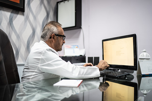 Senior doctor using computer in his office at the hospital