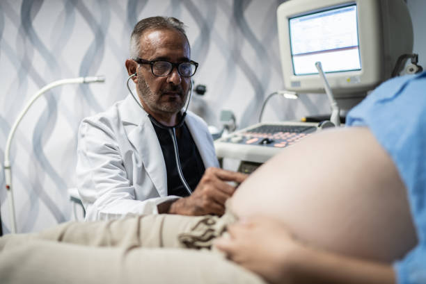 ginecologo che controlla la donna incinta con lo stetoscopio nel suo ufficio - human pregnancy midwife healthcare and medicine visit foto e immagini stock