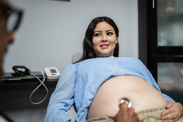 ginecologo che controlla la donna incinta con stetoscopio nel suo ufficio - human pregnancy midwife healthcare and medicine visit foto e immagini stock