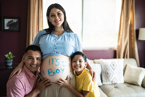 Portrait of family doing gender reveal at the living room at home