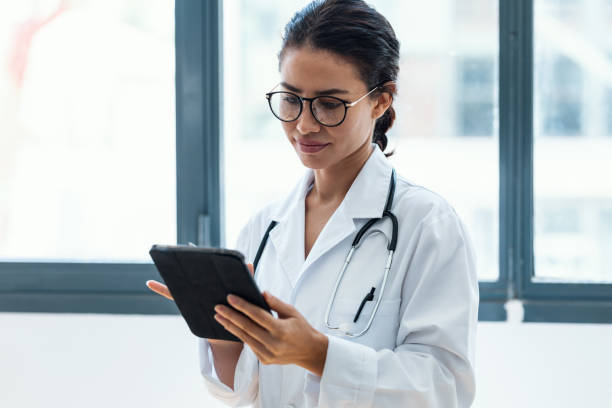 istock Female doctor using her digital tablet while standing in the consultation. 1418526791