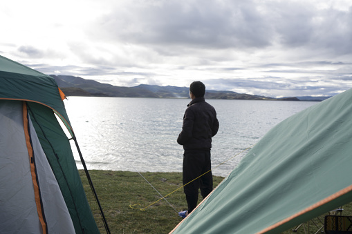 Young male migrant pitching tent against his family in refugee camping