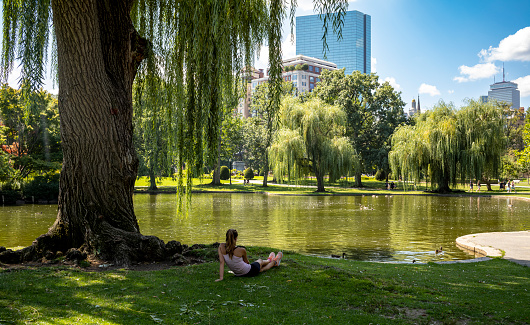 Photo showing a woman relaxing on a warm summer afternoon in the Boston Public Garden in downtown Boston, MA