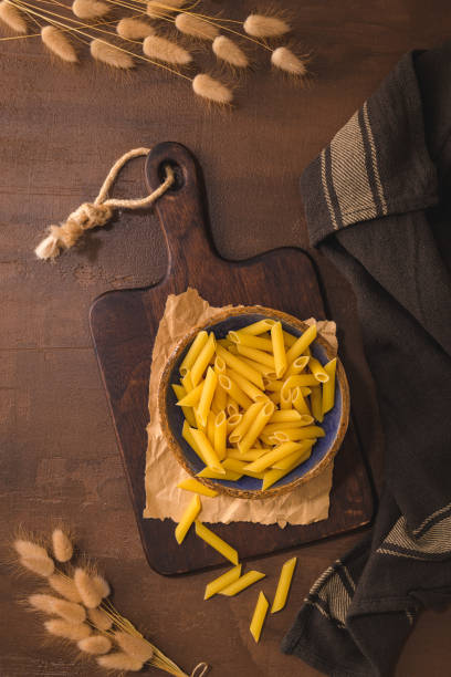 Penne pasta in wooden cutting board