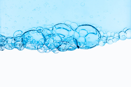 Transparent background with blue bubbles. Backdrop with effervescent bubbles of gas, oil in the texture of water. The concept of cosmetic background for oxygen skin care and cleansing. Texture of two-phase oil close-up.