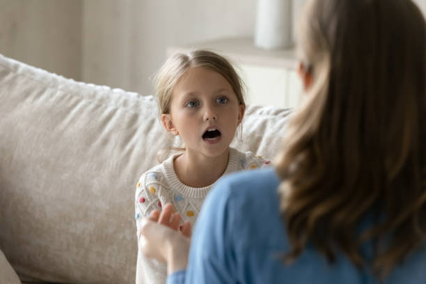 Speech therapist helping kid with pronunciation problems, stock photo