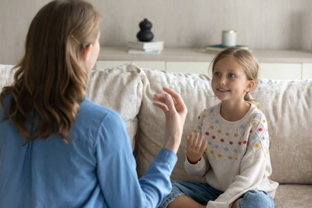 terapeuta feminina ensinando menina bonita criança a falar linguagem gestos - stutter - fotografias e filmes do acervo