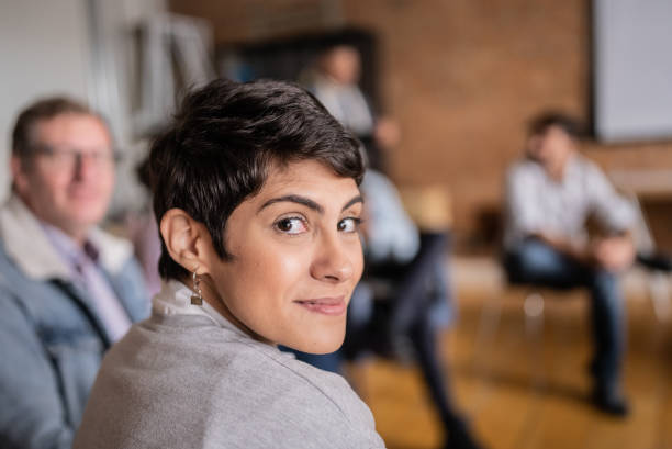 porträt einer jungen frau, die im klassenzimmer, in der gruppentherapie oder im seminar sitzt - learning education chair circle stock-fotos und bilder