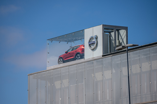 Gothenburg, Sweden - June 04 2022: Red Volvo car in a display box on the roof of a car dealership.