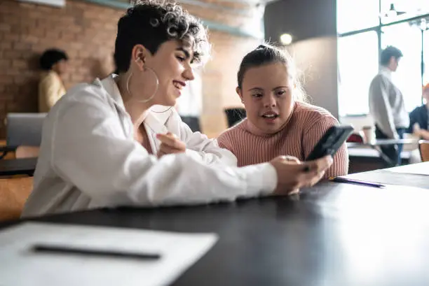 Photo of Colleagues talking and using smartphone in the classroom - including woman with special needs