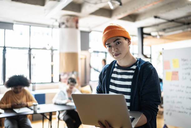 portrait d’un jeune homme tenant l’ordinateur portable dans la salle de classe ou la petite entreprise - presentation business adult student seminar photos et images de collection