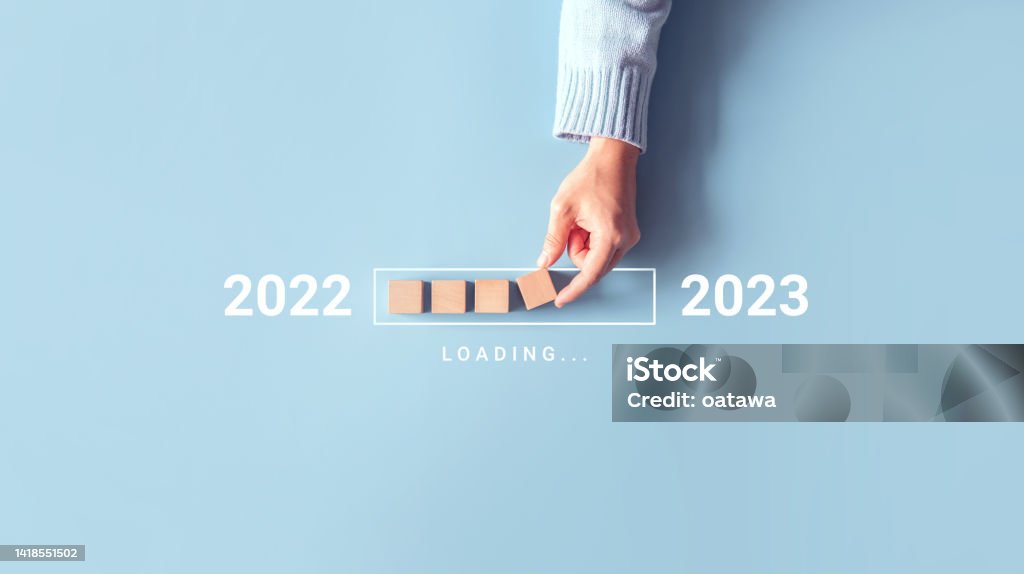 Loading new year 2022 to 2023 with hand putting wood cube in progress bar. Start new year 2023 with goal plan, goal concept, strategy. 2023 Stock Photo