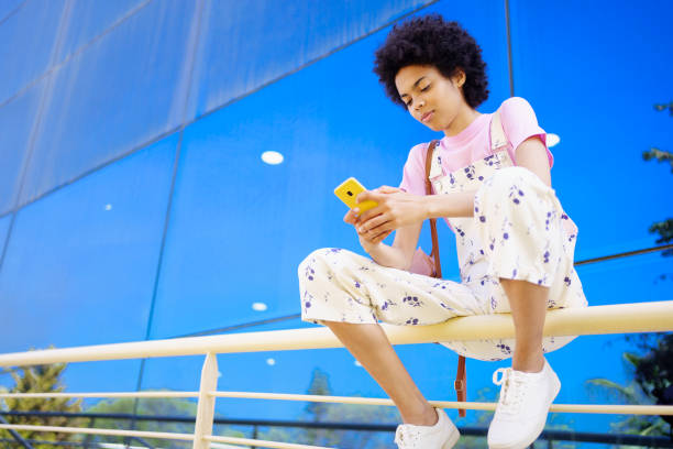 istock Black woman surfing cellphone on railing 1418556349
