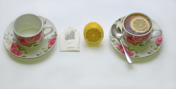 Top view of a cup of tea with tea bags and lemon on a white background. tea preparation concept. empty cup, tea bag, lemon and boiling water. an invigorating fragrant drink