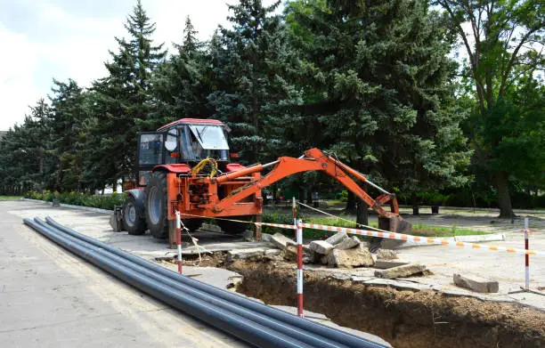 Laying of urban communications. plastic pipes lie next to the trench. replacement of rusty metal pipes with new plastic ones. A trench dug by a tractor