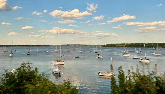Travelling by Amtrak, from Boston to Old Saybrook, along the shoreline, a picturesque view of the sailing boats in Greenwich Bay, East Greenwich. The State of Rhode Island was one of the original 13 states and is one of the six New England states. Rhode Island is bounded to the north and east by Massachusetts, to the south by Rhode Island Sound and Block Island Sound of the Atlantic Ocean, and to the west by Connecticut. It is the smallest state in the union—only about 48 miles (77 km) long and 37 miles (60 km) wide.