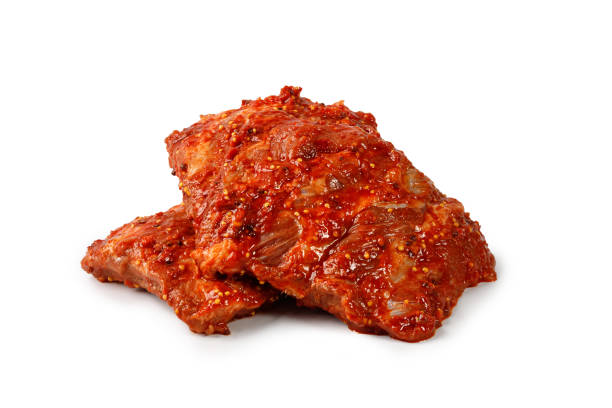 istock Pork marinated ribs for grill. Uncooked ribs in marinade, red sauce isolated on white background. Clipping path. 1418570832