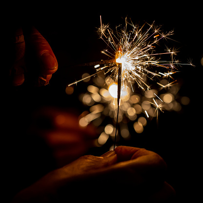 A sparkler being held at a party, with a shallow depth of field