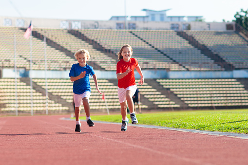 Child running in stadium. Kids run on outdoor track. Healthy sport activity for children. Little girl and boy at athletics competition race. Young athlete training. Runner exercising. Jogging for kid.