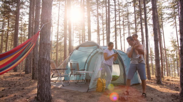 Family camping in nature at sunset. Tent in woods.