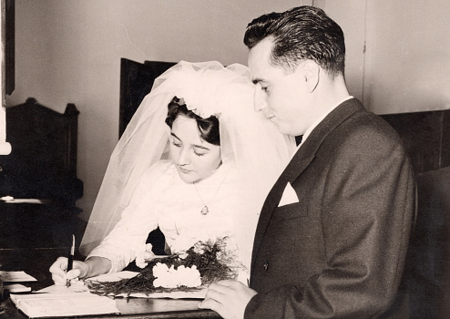 Vintage image from the 50s : Young couple signing their wedding documents