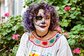 portrait latin young woman with La Calavera Catrina makeup with plants and flowers in the background
