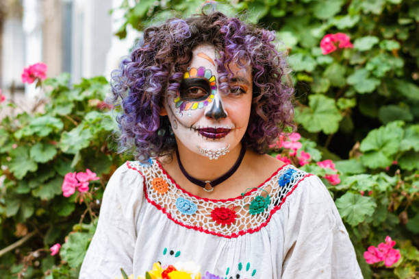 portrait latin young woman with La Calavera Catrina makeup with plants and flowers in the background stock photo